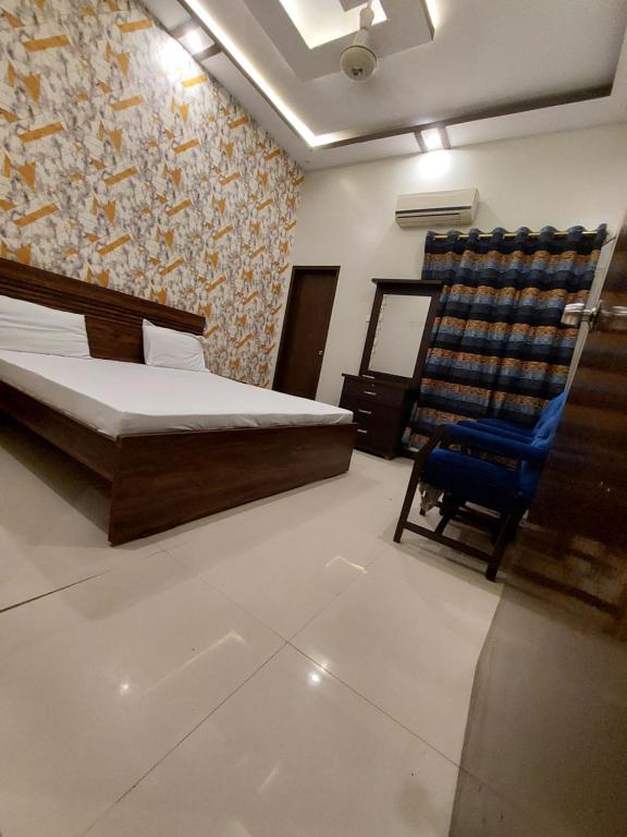a bedroom with a bed and a blue chair at Karachi Guest House in Karachi