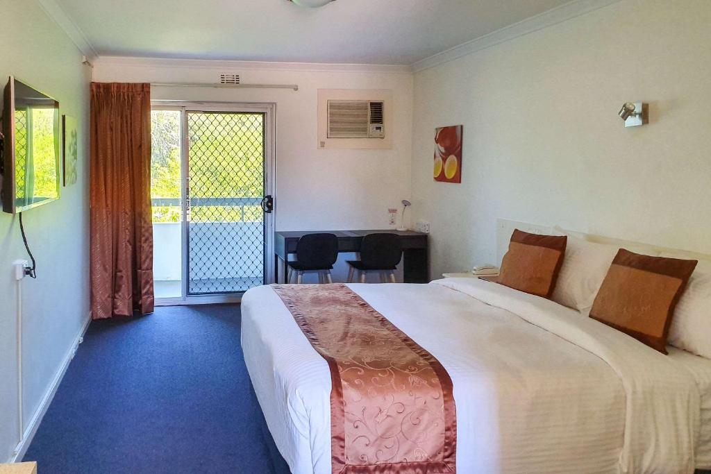 a hotel room with a large bed and a balcony at Econo Lodge Rivervale in Perth