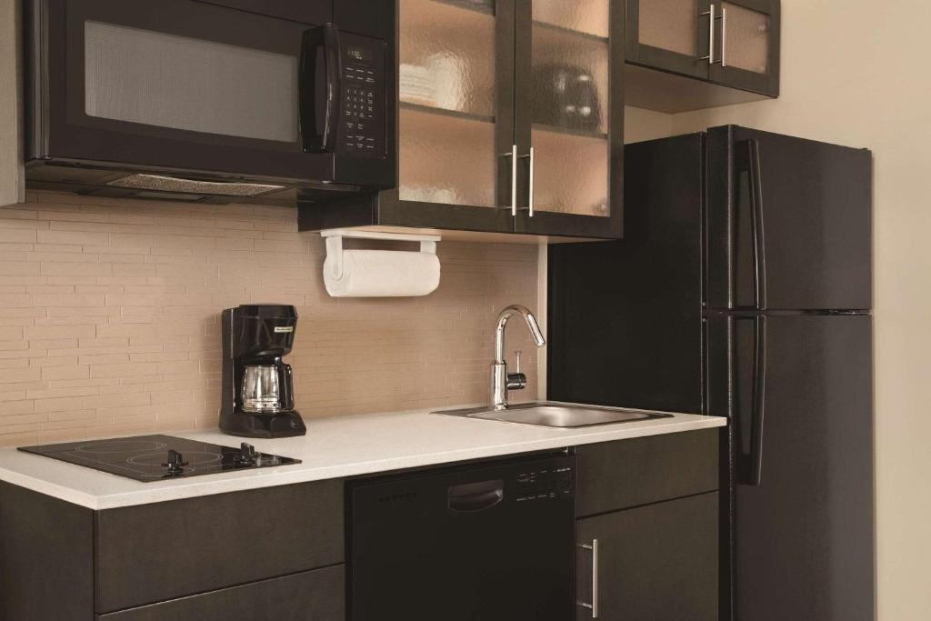 a kitchen with a sink and a black refrigerator at Park Inn by Radisson, Calgary Airport North, AB in Calgary