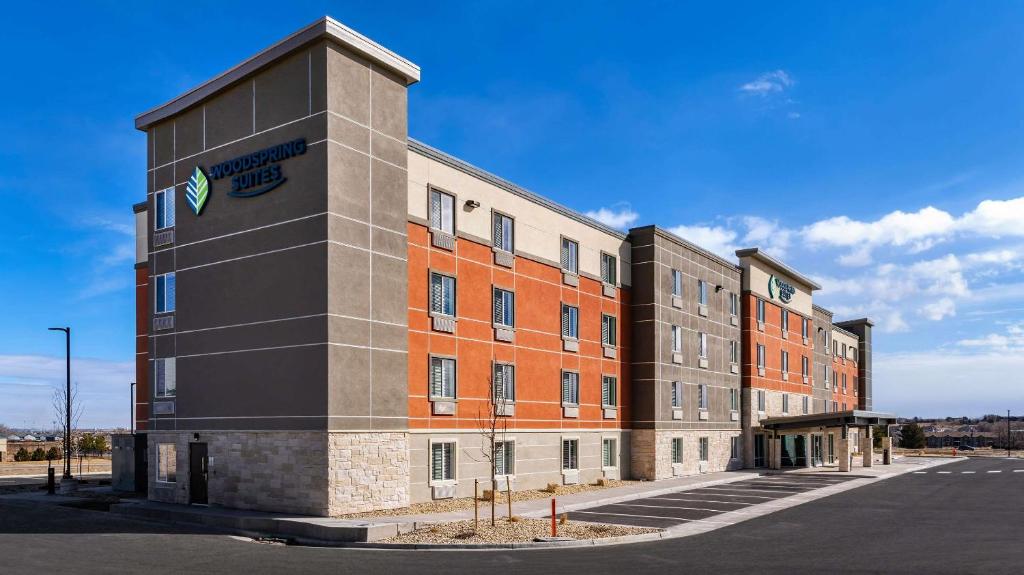 un gran edificio con un cartel en el costado en WoodSpring Suites Greeley, en Greeley