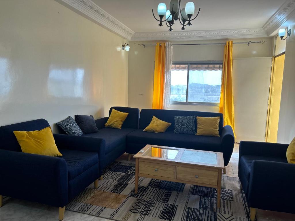 een woonkamer met een blauwe bank en gele kussens bij Appartement meublé F4 Maristes, Dakar in Dakar