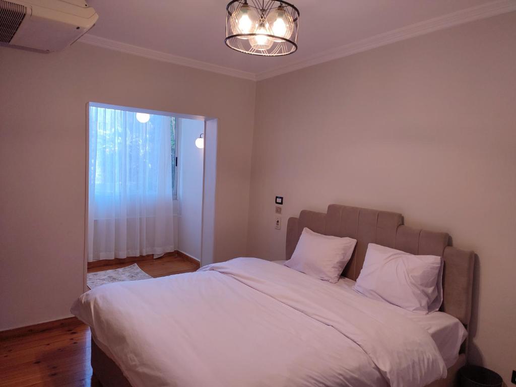 - une chambre avec un lit doté de draps blancs et une fenêtre dans l'établissement شقة فندقية فاخرة هادئة في القاهرة الدقي, au Caire