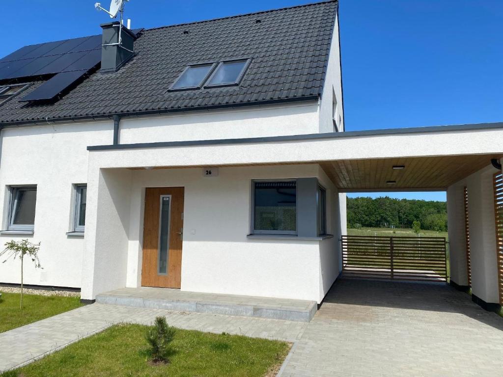 a white house with a solar roof at Ferienhaus in Trzsacz mit Terrasse, gemeinschaftlichem Pool und Grill in Trzęsacz