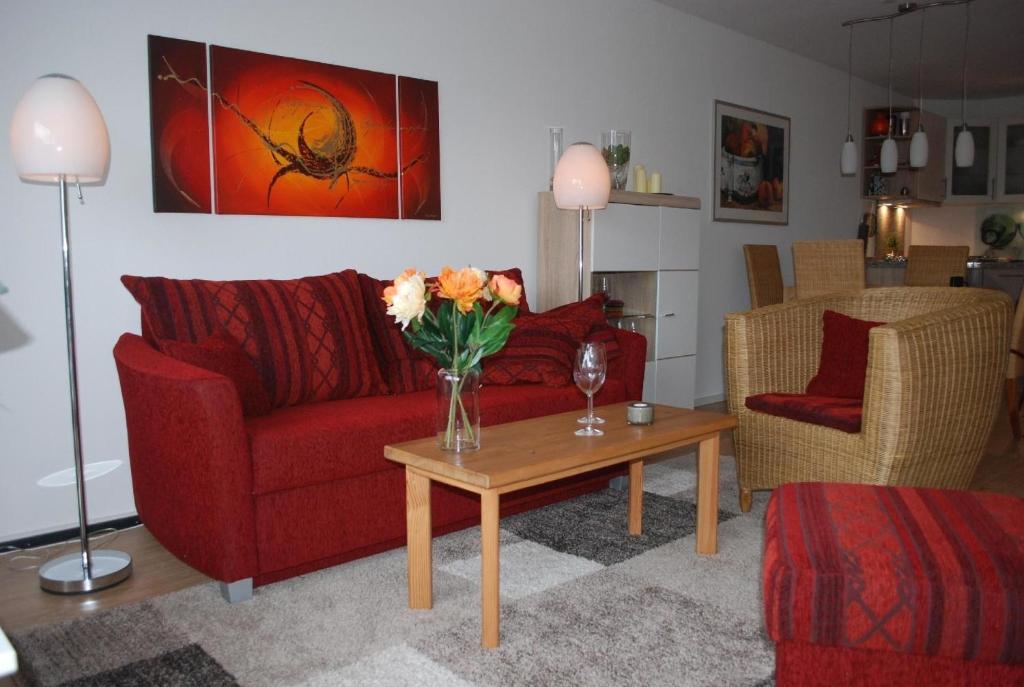sala de estar con sofá rojo y mesa con flores en Ferienwohnung mit Balkon in Hohegeiß, en Braunlage