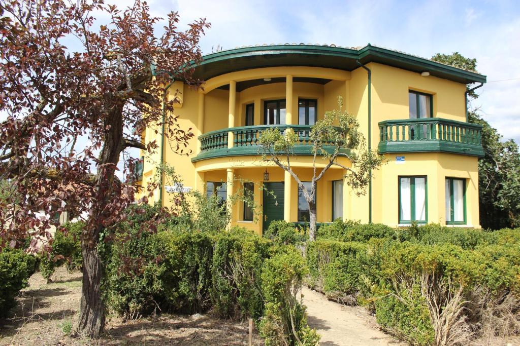 una casa amarilla con techo verde en Hotel Valle del Oja en Casalarreina