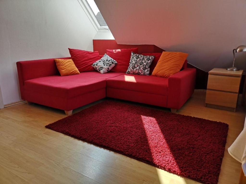 a red couch in a living room with a red rug at Ganzes Haus - 120qm Ruheoase bei Berlin S-Bahn nah in Kolonie Röntgental