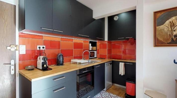 - une cuisine avec du carrelage noir et orange sur le mur dans l'établissement Le Delicious avec Terrasse - Hyper Centre, à Rennes