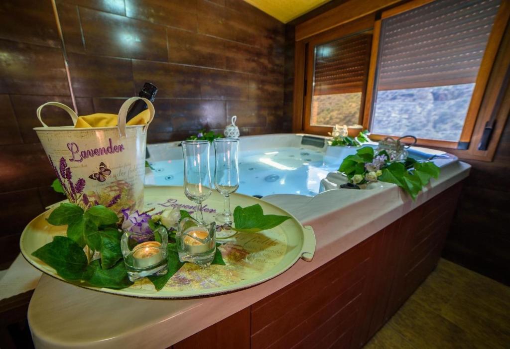 eine Badewanne mit einem Teller mit Speisen und Weingläsern in der Unterkunft Ferienhaus in Laroya mit Whirlpool, gemeinschaftlichem Pool und Grill in Laroya