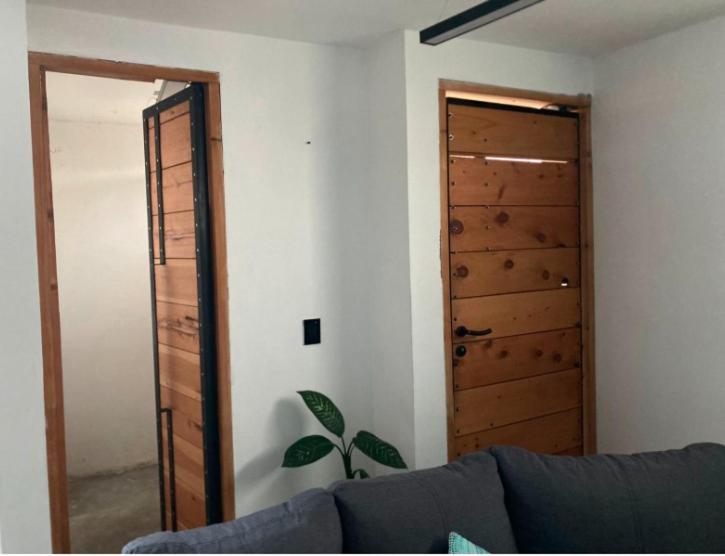 uma sala de estar com um sofá e uma porta de madeira em Apartamento Loft Centrico Amecameca em Amecameca de Juárez