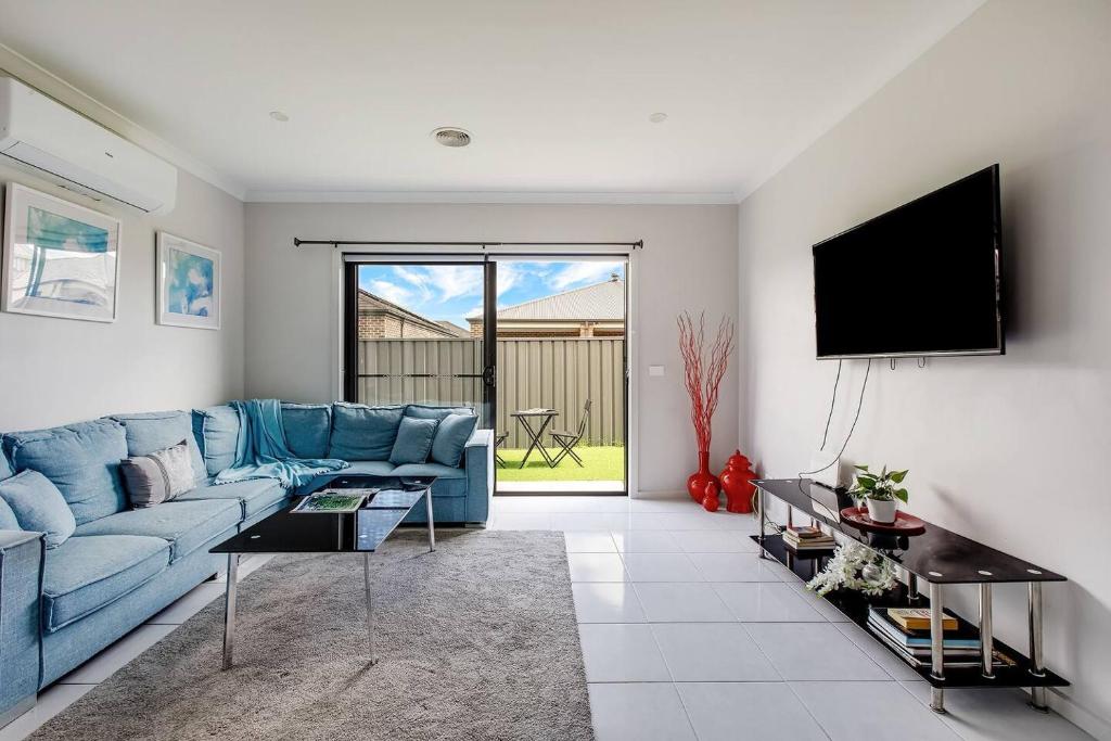 ein Wohnzimmer mit einem blauen Sofa und einem Flachbild-TV in der Unterkunft Melton Moments - Cheerful and Breezy Living in Melton