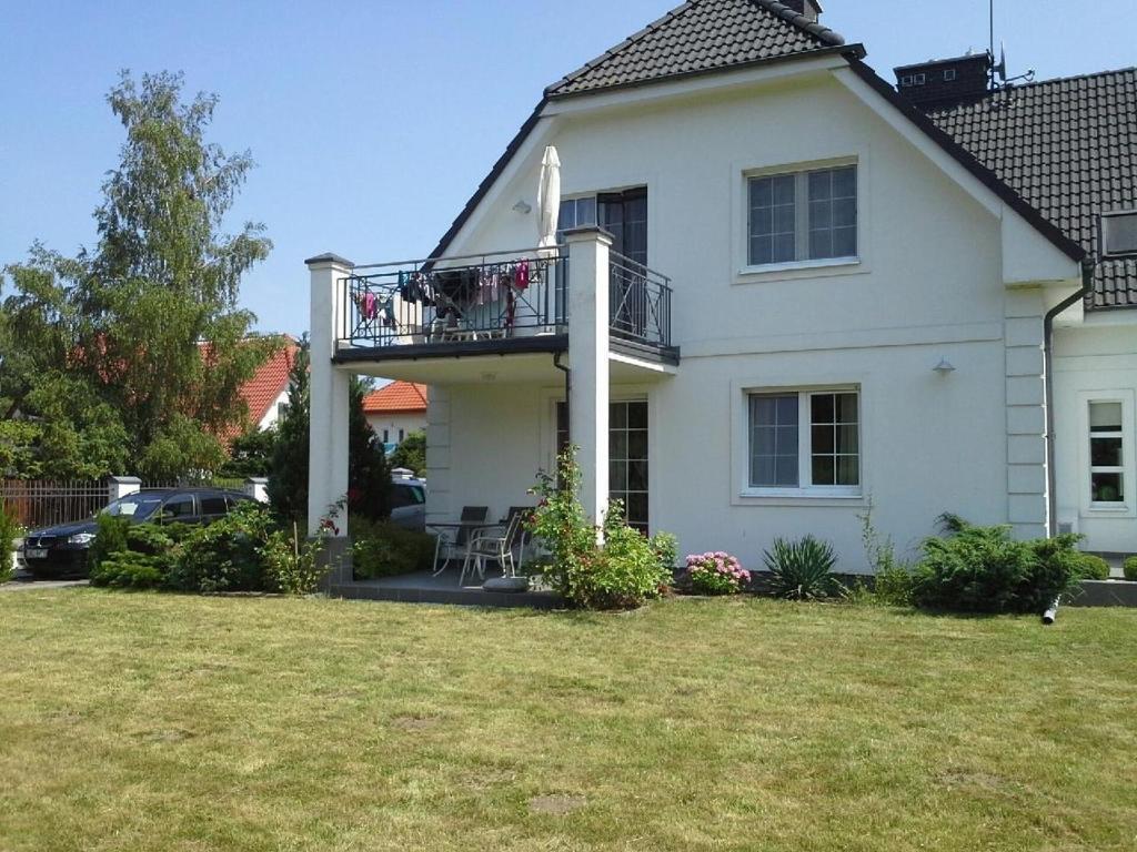 a white house with a balcony and a yard at Wohnung in Rowy mit Grill, Terrasse, Parkplatz und Garten in Rowy