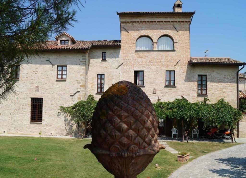 un gran edificio de piedra con una gran estatua de piña delante de él en Ferienhaus in Piosina mit Garten, Whirlpool und Grill, en Città di Castello