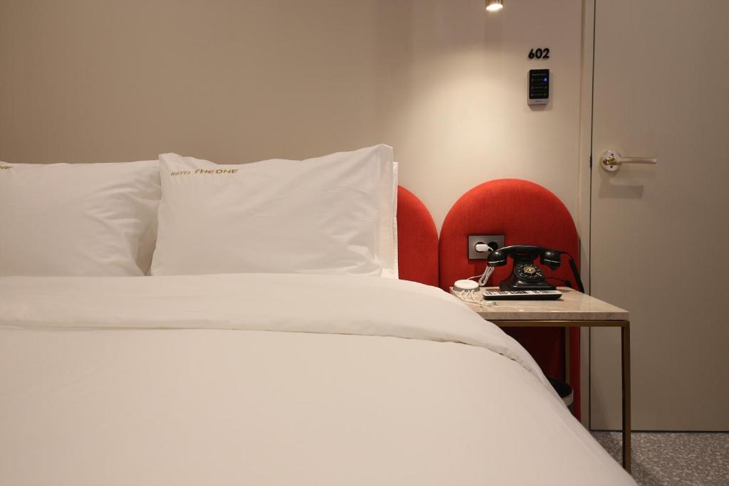 a bedroom with a white bed and a red chair at Hotel The One in Gangneung