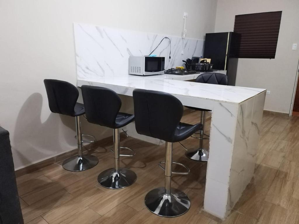 a kitchen with a white counter with chairs and a microwave at Casa Vacacional 2 Pisos in Mazatlán