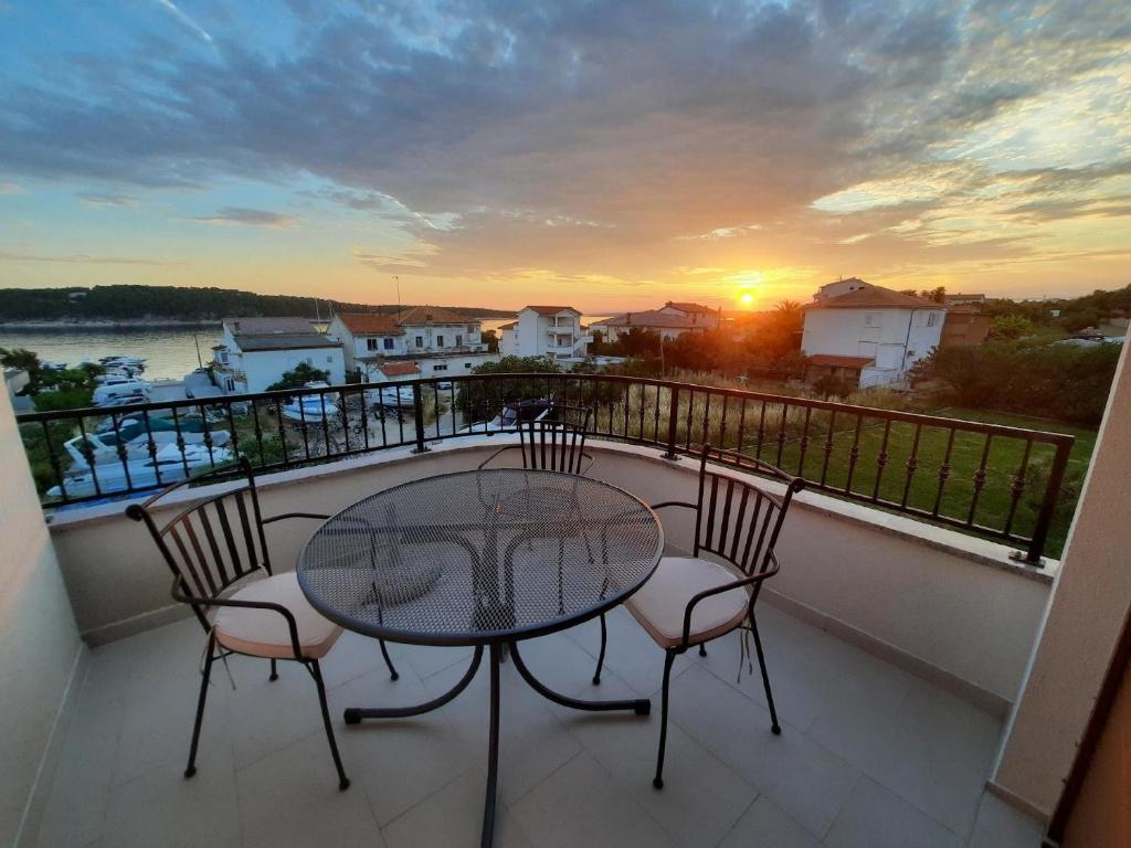 una mesa y sillas en un balcón con puesta de sol en Tolle Wohnung in Barbat mit Möbliertem Balkon, en Barbat na Rabu