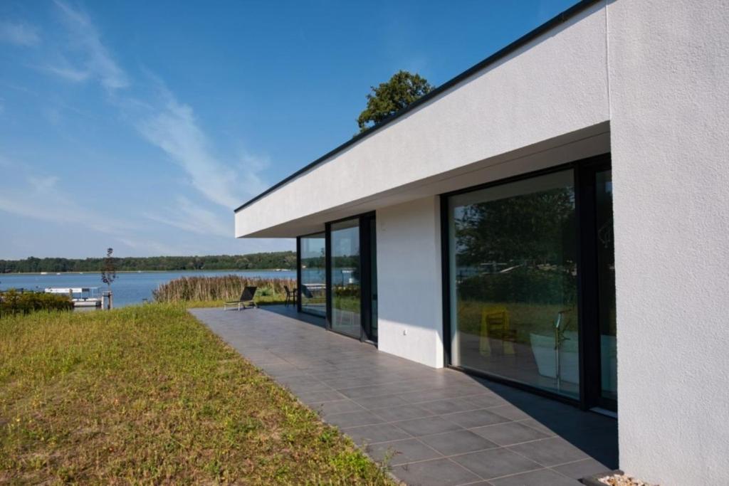 a building with large glass windows next to a body of water at Haus am See Storkow in Storkow