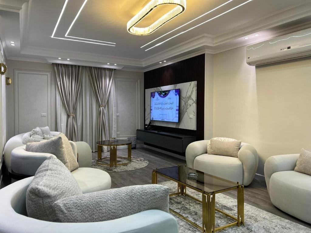 a living room with white furniture and a flat screen tv at دار عزه in Cairo
