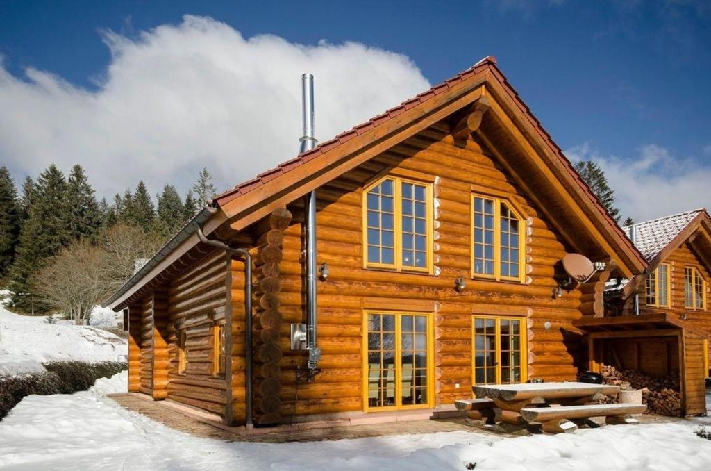 eine Blockhütte im Schnee mit einem Picknicktisch in der Unterkunft Traumhafte Ferien im Schwarzwald-Chalet Die perfekte Location für Premium Sommer-und Skiurlaube in Neuglashütten