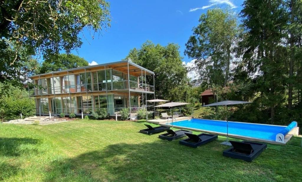una casa grande con piscina en el patio en Sportives Ökologisches Lifestyle-Ferienhaus mit großem Außenpool, Sauna und Fitnessbereich en Donaueschingen