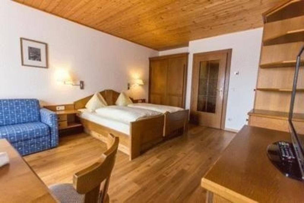 a hotel room with a bed and a blue couch at Wohnung in Sankt Oswald mit Terrasse, Grill und Garten in Bad Kleinkirchheim