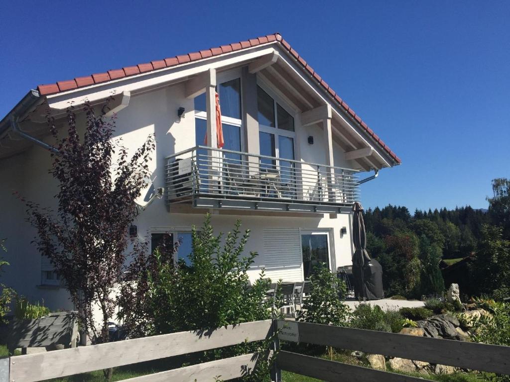 une maison blanche avec un balcon sur une colline dans l'établissement Tolle Wohnung in Ofterschwang mit Eigener Sauna und Bergblick, à Ofterschwang
