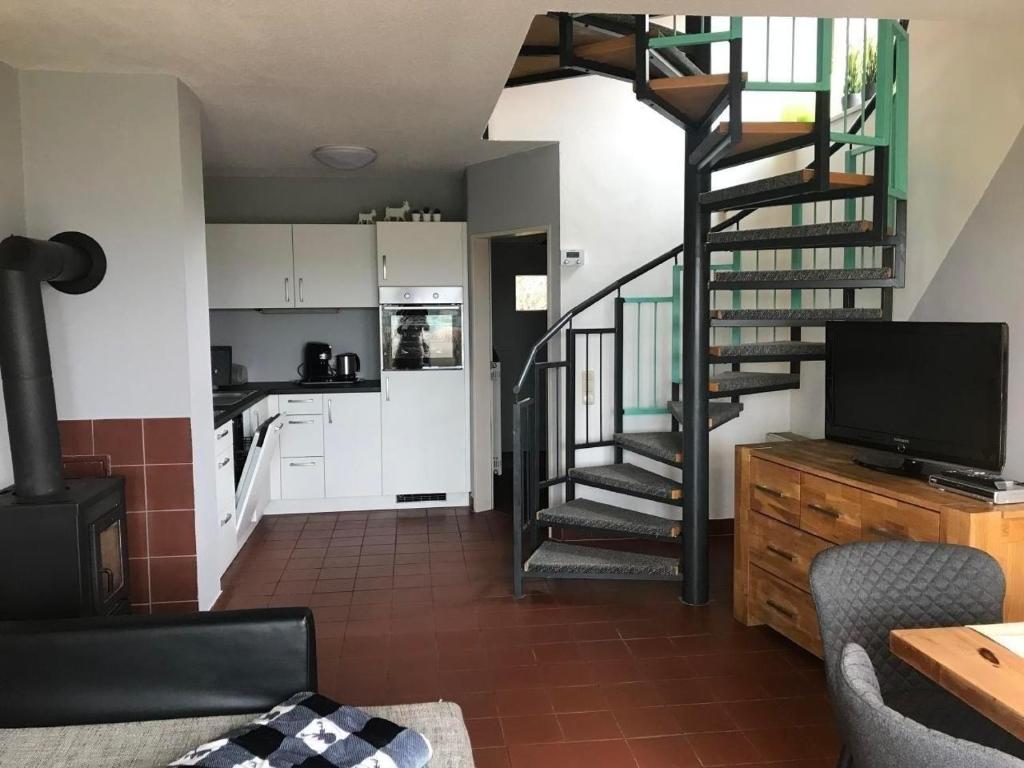 a living room with a spiral staircase and a kitchen at Hundefreundliches Ferienhaus in Zandt mit Terrasse, Grill und Garten in Zandt
