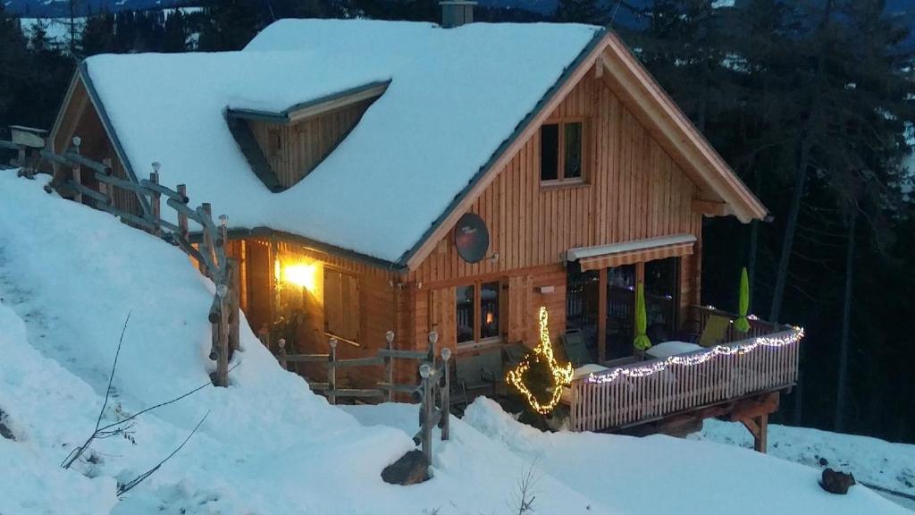 une cabane en rondins avec de la neige sur le toit dans l'établissement Die Berghexn, am Klippitztörl, à Bad Sankt Leonhard im Lavanttal