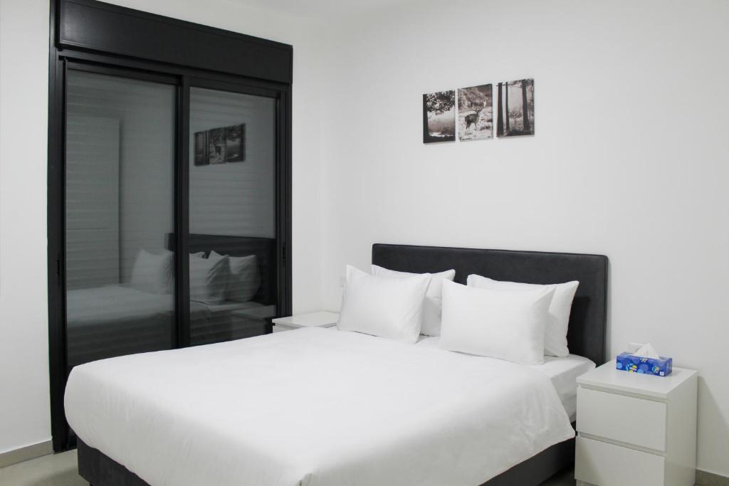 1 dormitorio con 1 cama blanca grande y espejo en Suite Apartment #21 By Hashdera Eilat, en Eilat