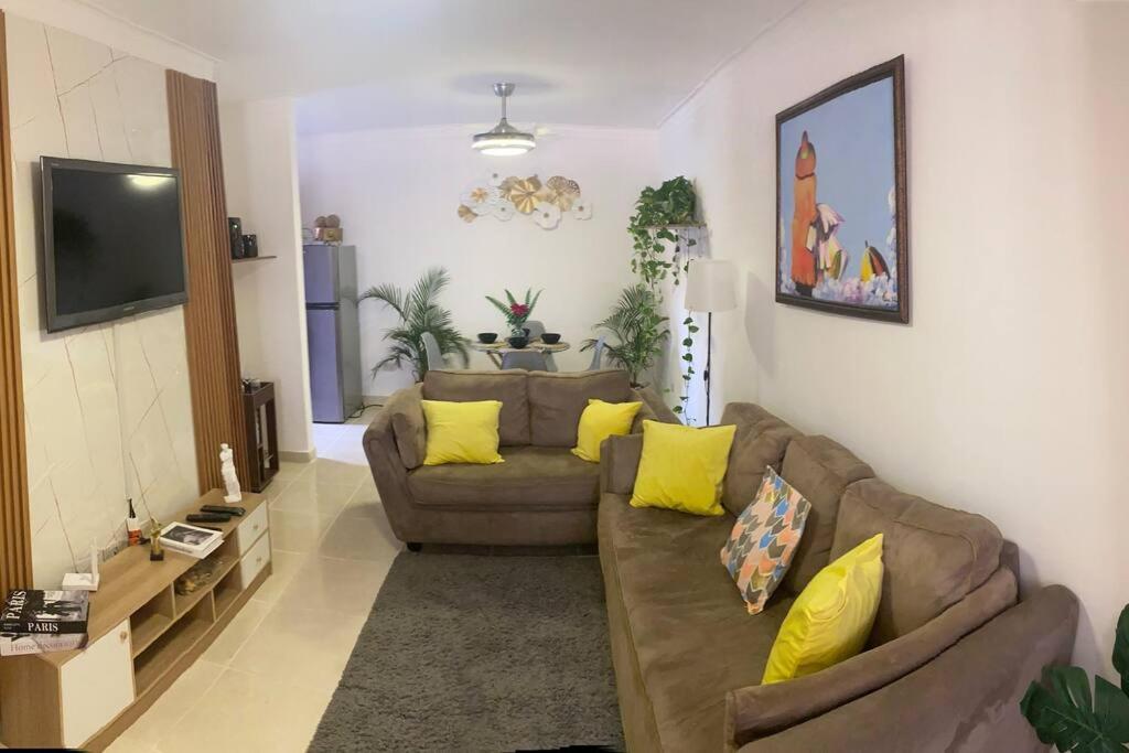 a living room with a brown couch and yellow pillows at Acogedor apartamento amueblado in Los Paredones