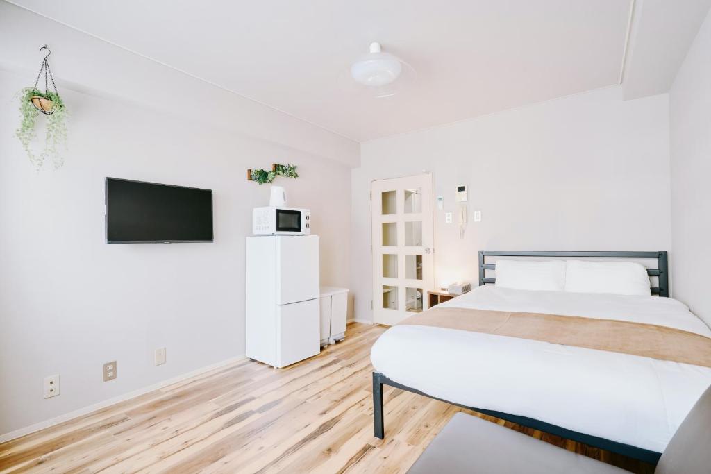 a white bedroom with a bed and a tv at Shibuya Apartment Room Dogenzaka in Tokyo