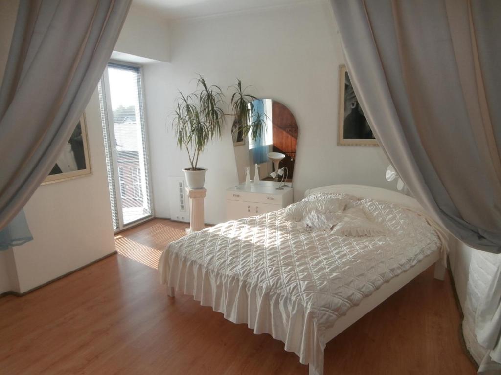 a white bedroom with a bed and a window at Private Apartment For You in Tartu