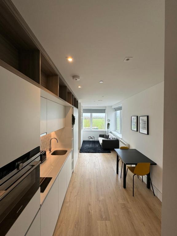 New Bedfont的住宿－London LuXXe Suites & Apartments - London Heathrow Airport, Terminal 1 2 3 4 5，厨房以及带桌子和沙发的客厅。