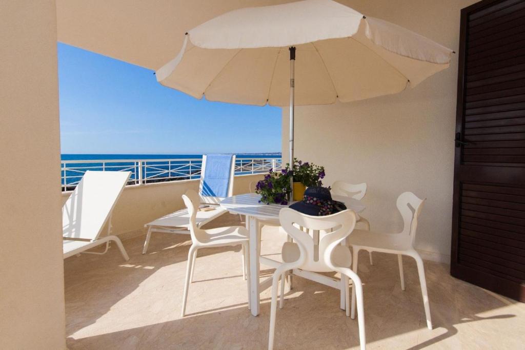 una mesa y sillas en un balcón con sombrilla en Ferienhaus für 6 Personen ca 80 qm in Trappeto, Sizilien Nordküste von Sizilien, en Trappeto