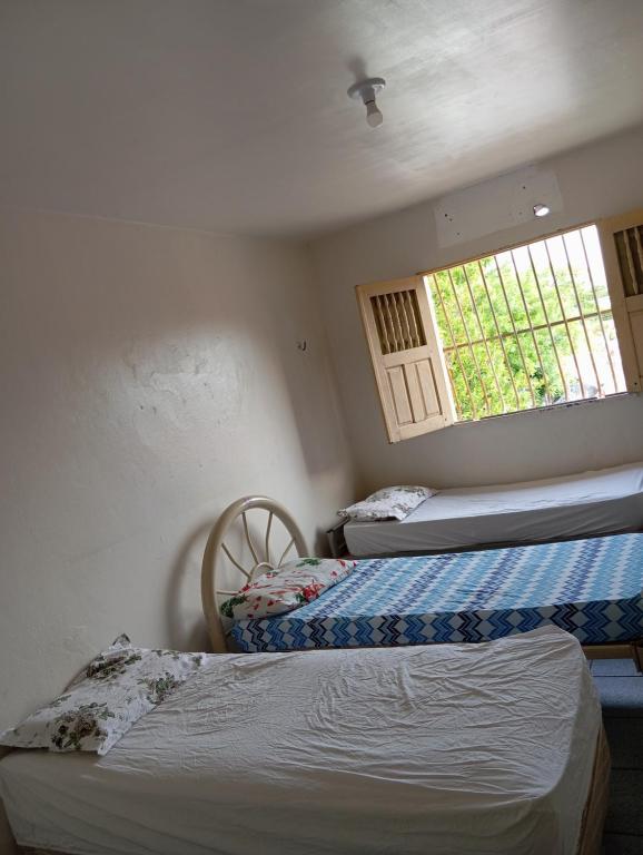 two beds in a room with a window at Hostel Teresina in Teresina