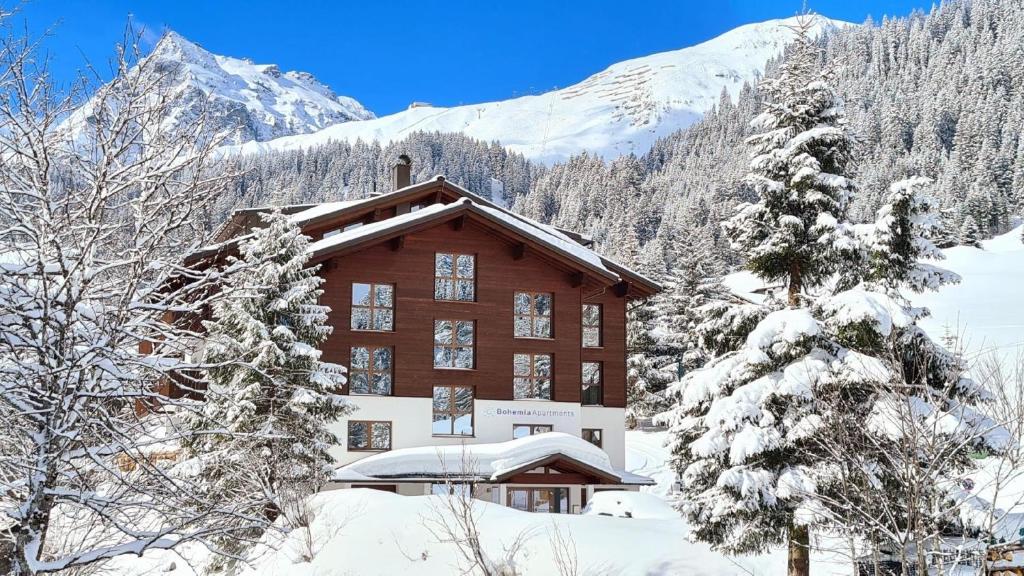 un bâtiment dans la neige avec des montagnes en arrière-plan dans l'établissement Moderne Ferienwohnung in Gargellen mit 2 Schlafzimmern - b57751, à Sankt Gallenkirch