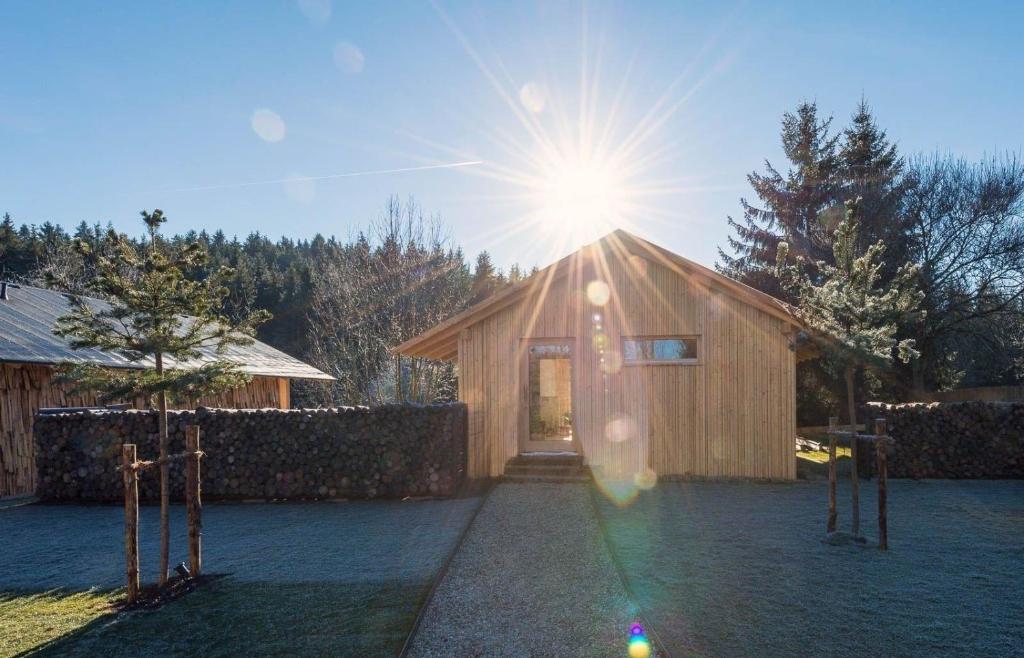 um pequeno edifício de madeira com o sol brilhando atrás dele em Ferienhaus für 2 Personen ca 87 qm in Regen-Kattersdorf, Bayern Bayerischer Wald em Regen