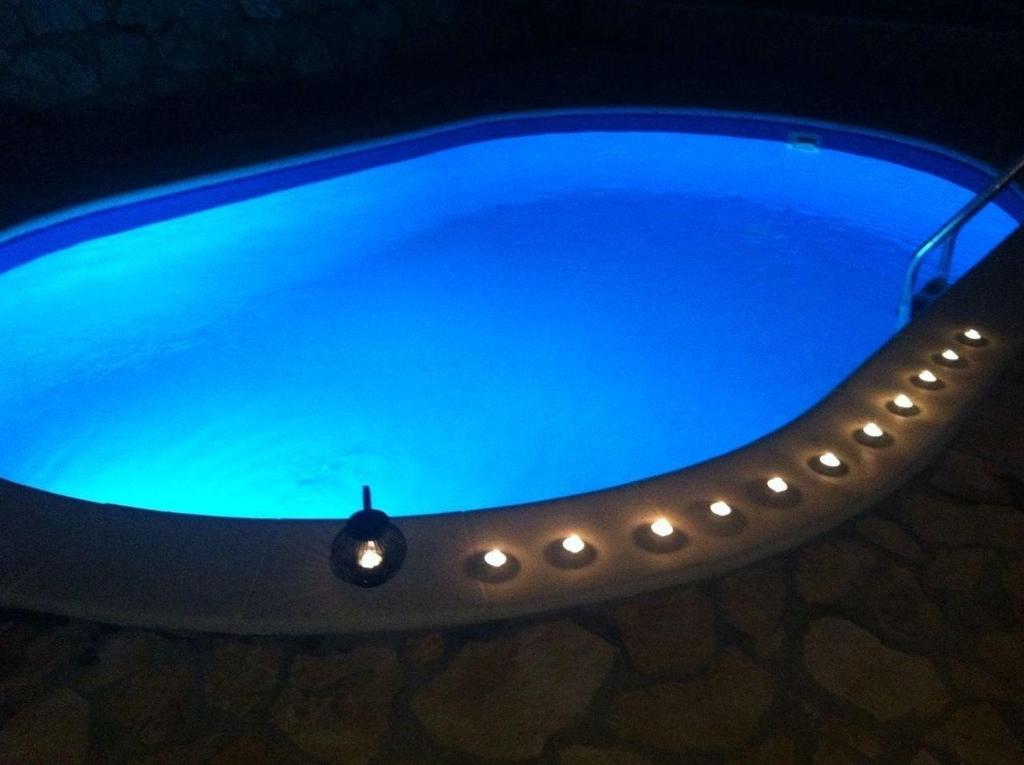 una piscina azul con una luz encendida en Strandnahe Ferienwohnung mit Balkon und Gemeinschaftspool, in der Nähe des Naturparks Velebit en Cesarica