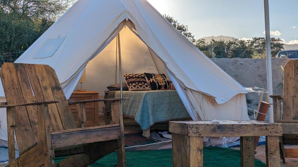a white tent with a bed and two chairs at La Window Glamping in La Ventana