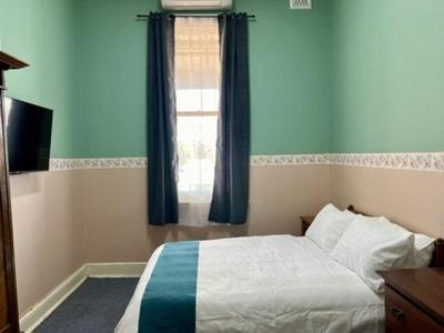 een slaapkamer met een bed met blauwe muren en een raam bij The Exchange Pingelly in Pingelly
