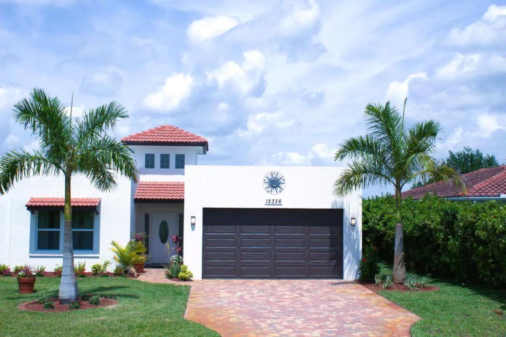 a white house with a garage and two palm trees at Lake Marlin Villa in Port Charlotte