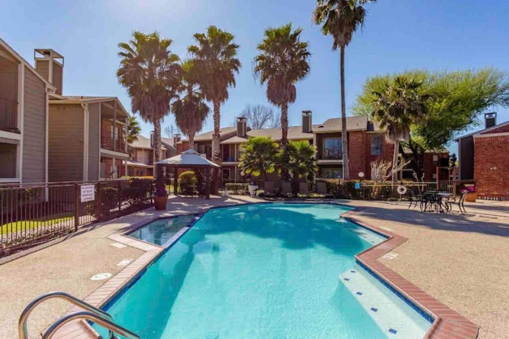 uma piscina com palmeiras e edifícios em Luxurious Apt With King Bed-MedCenter-Free Parking em Houston