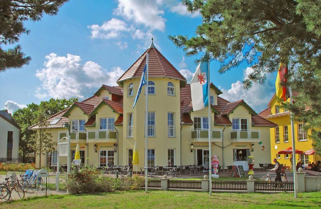 una gran casa amarilla con banderas delante en Hotel Ostseeblick, en Ostseebad Karlshagen