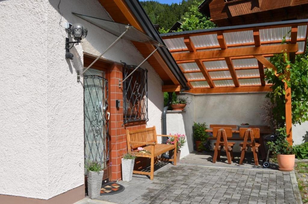 un patio con pérgola de madera, mesa y sillas en Charmante Ferienwohnung in Gemeinde Flattach mit Beheiztem gemeinsamem Pool en Flattach