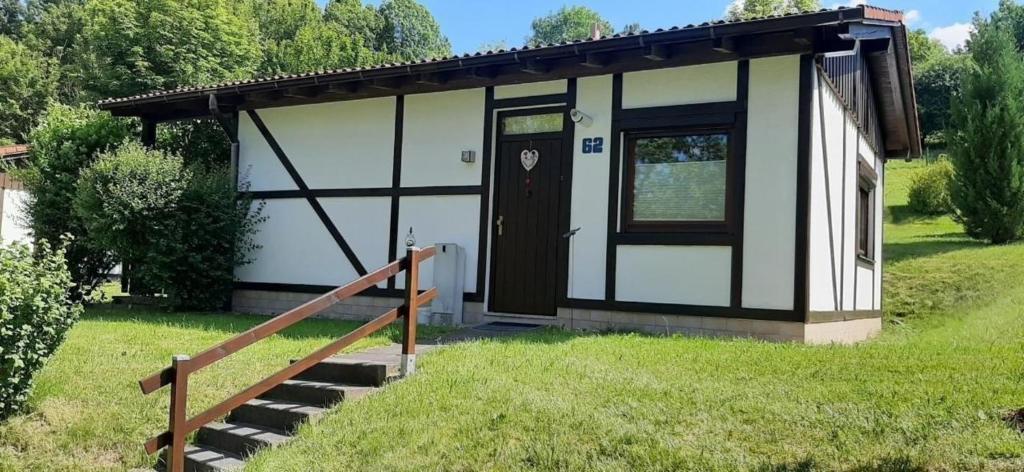 un pequeño edificio blanco y negro con una puerta en Gemütliches Ferienhaus Bungalow SixtyTwo in Dipperz-Dörmbach en Dipperz