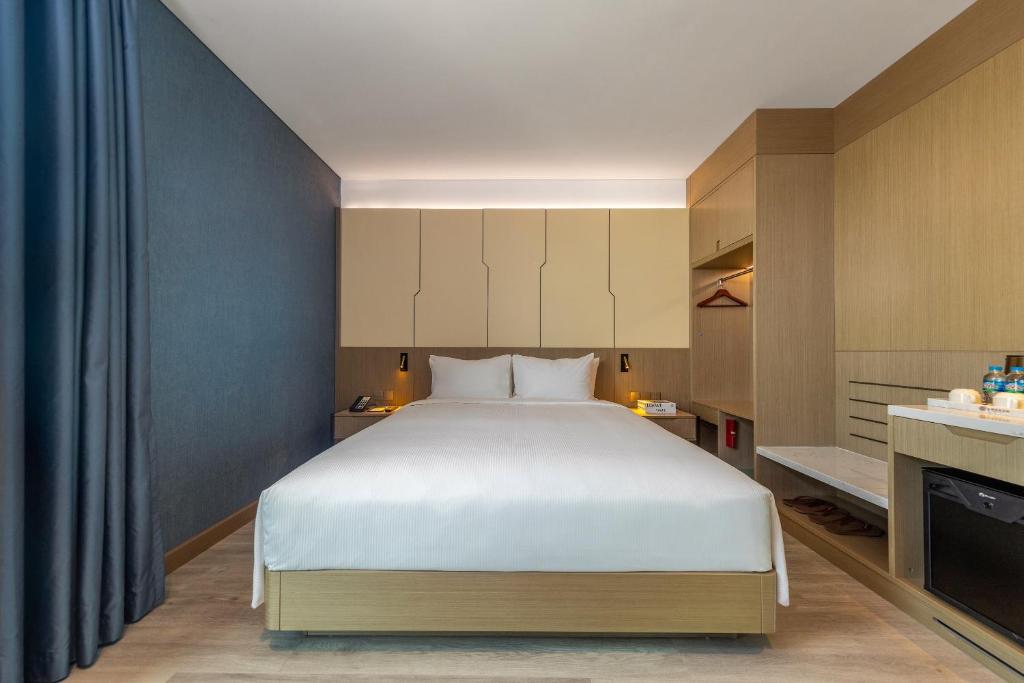 A symmetrical bedroom with a centered bed, dark blue wall and built-in wardrobe storage.