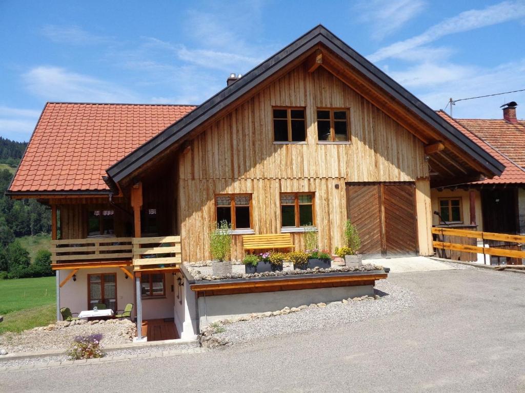 a large wooden house with a roof at Direkt am Waldrand gelegene Ferienwohnung, ideal für Wanderer im Sommer und Wintersportler in der kalten Jahreszeit in Oberstaufen