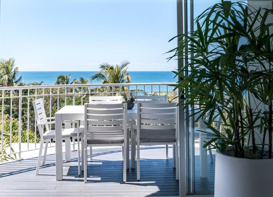 Una mesa y sillas en un balcón con la playa. en 10 Andari, Sunshine Beach ~ Beachside Luxury Home, en Sunshine Beach