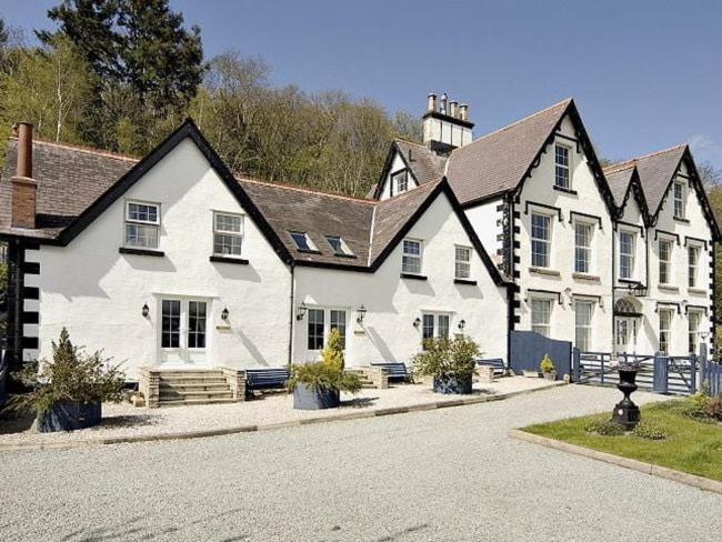 une grande maison blanche avec un toit noir dans l'établissement 3 Bed in Conwy TYPLL, à Llangelynin