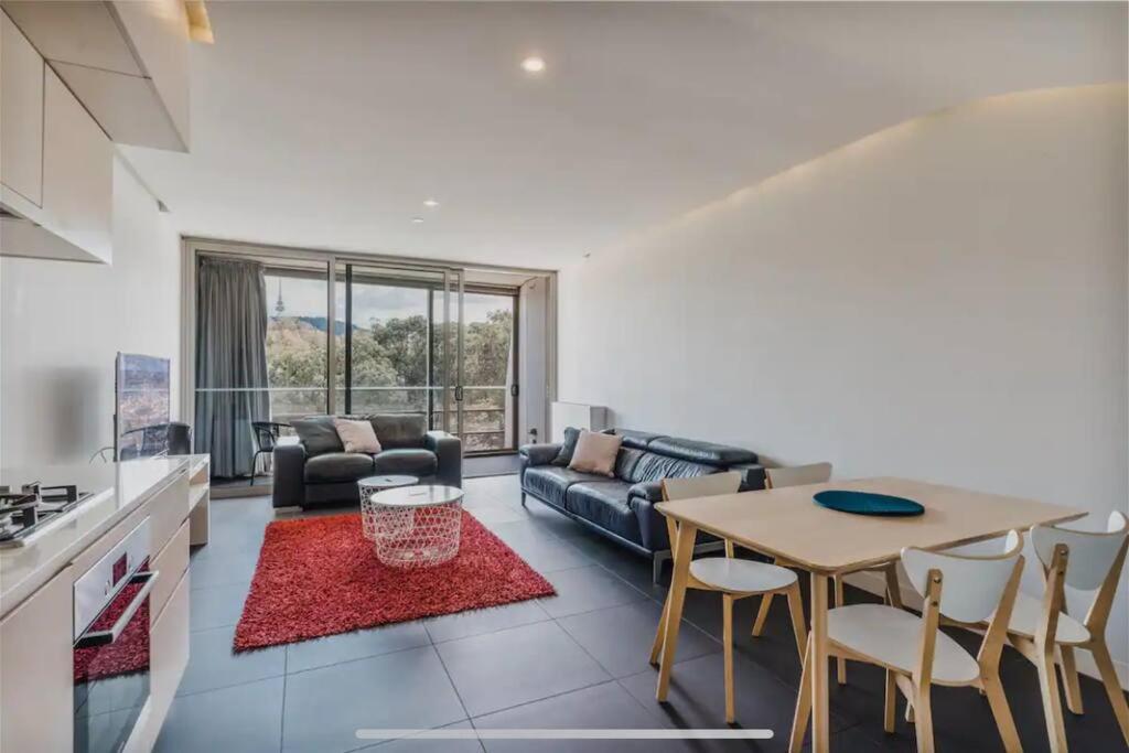 a kitchen and living room with a table and a couch at Apartment nestled between Lake Burley Griffin, city and ANU in Canberra