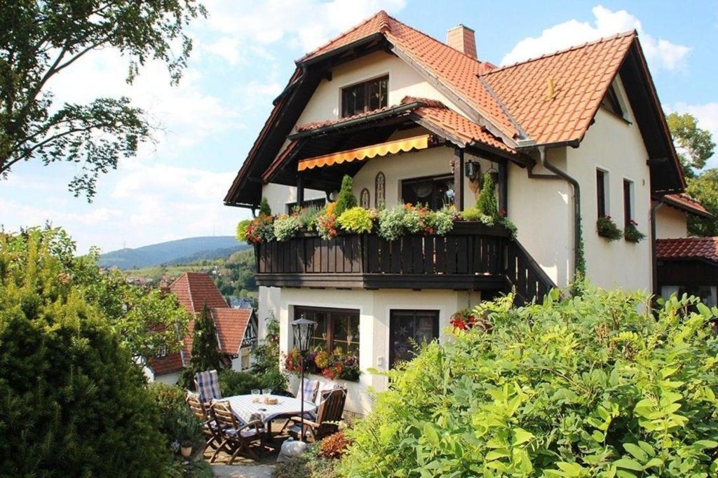 ein Haus mit einem Balkon mit Blumen darauf in der Unterkunft Große Ferienwohnung in Rauenstein mit Garten, Terrasse und Grill und Panoramablick in Rauenstein